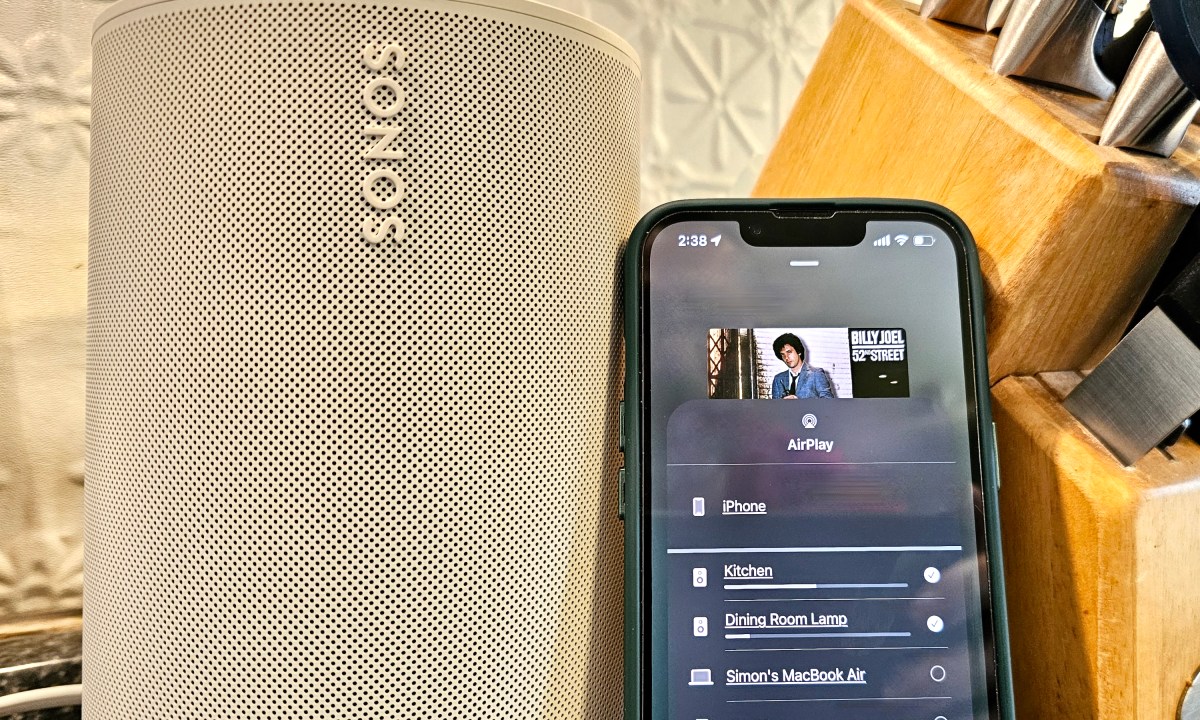 A Sonos Era 100 speaker next to an iPhone showing AirPlay speaker options.